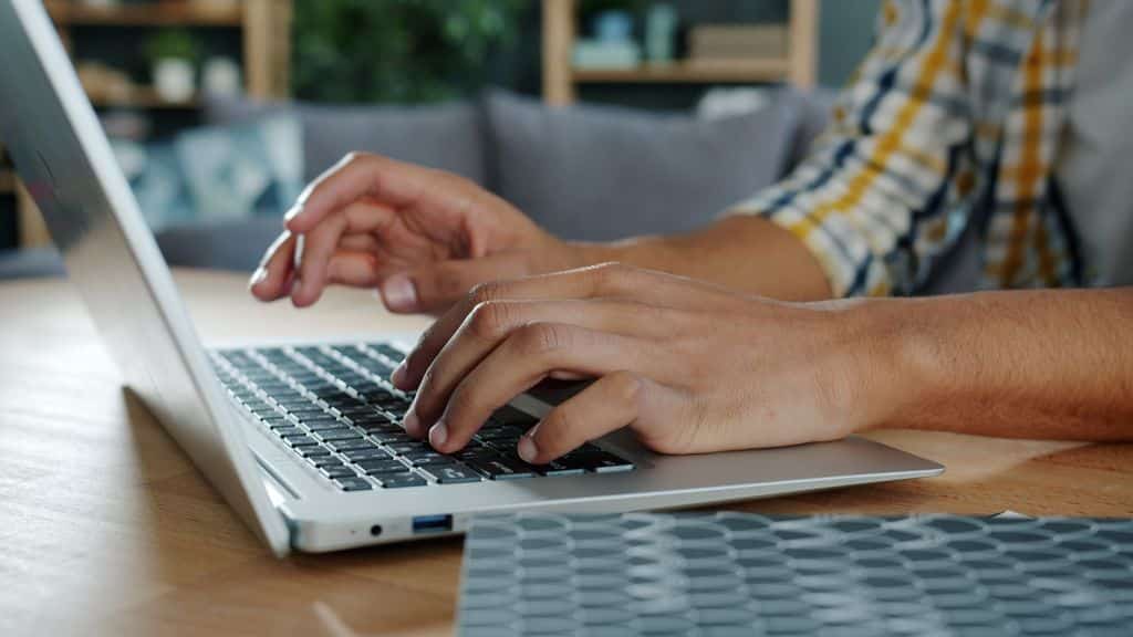 Close-up of hands typing on a laptop indoors, ideal for work-from-home themes.